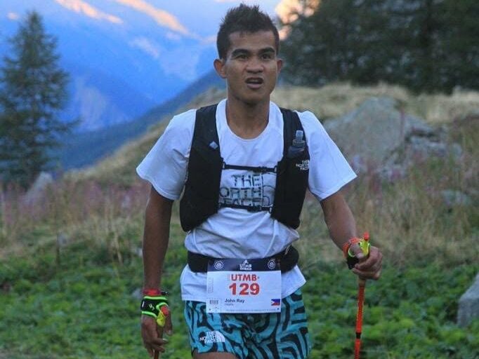 John Ray Onifa running on a mountain trail with poles during a UTMB race