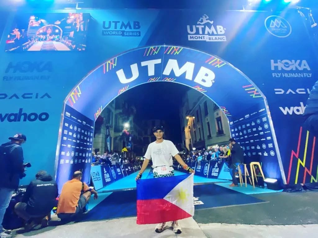 John Ray Onifa holding the Philippine flag at the UTMB finish arch in Chamonix